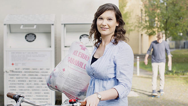 Kleidersammlung des DRK und Altkleidercontainer: junge Frau mit Altkleidersack vor einem Container des DRK- 2014